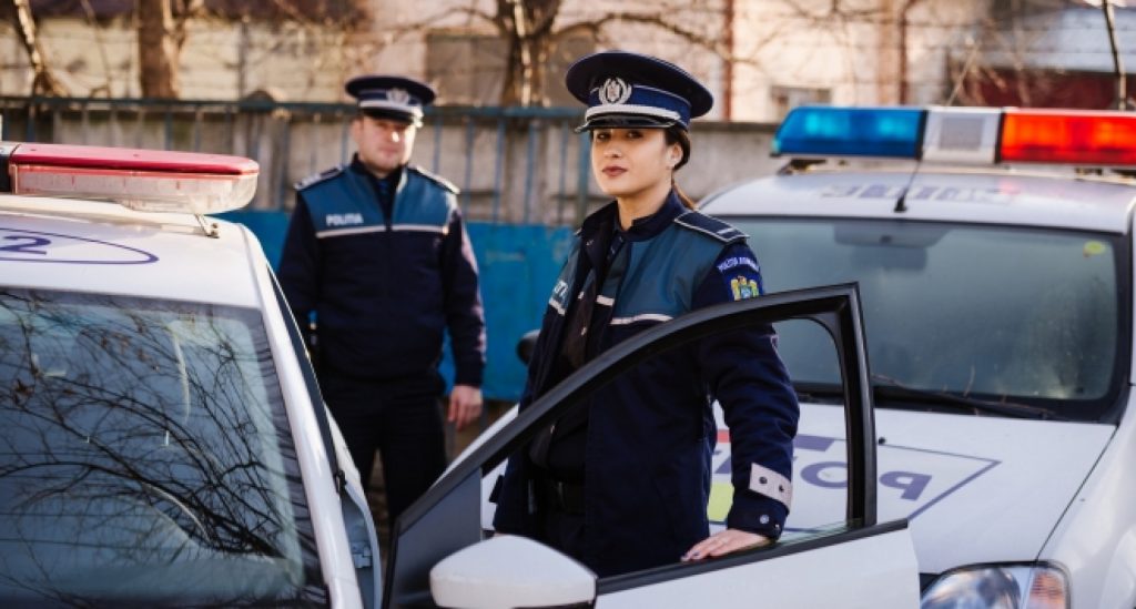 politisti in uniforme langa masini